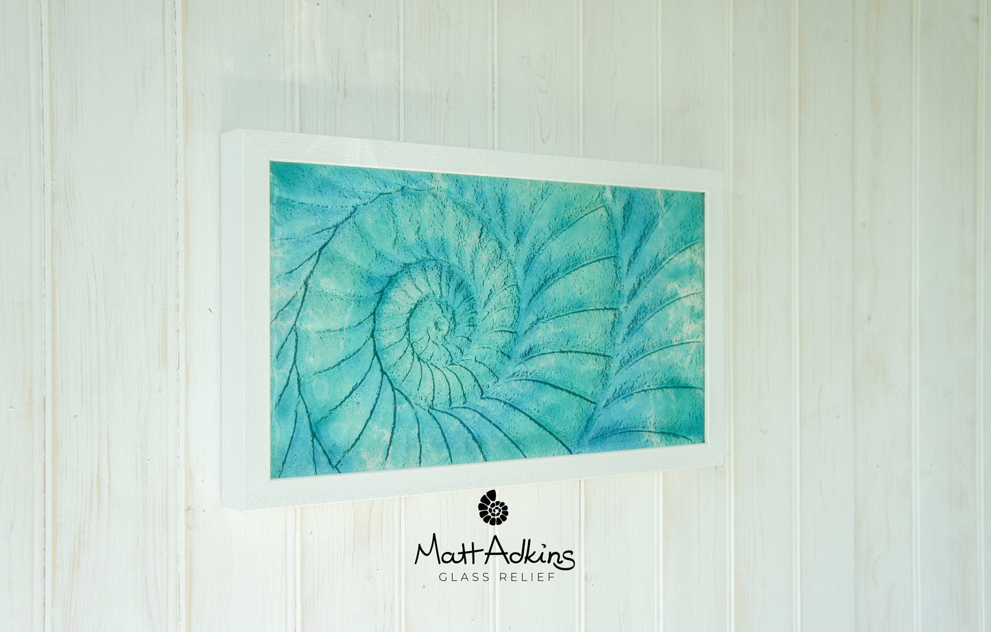 A medium-sized landscape-oriented ammonite frame with blue and turquoise colors in a swirl pattern, measuring 45x25 cm, with a white wooden frame.
