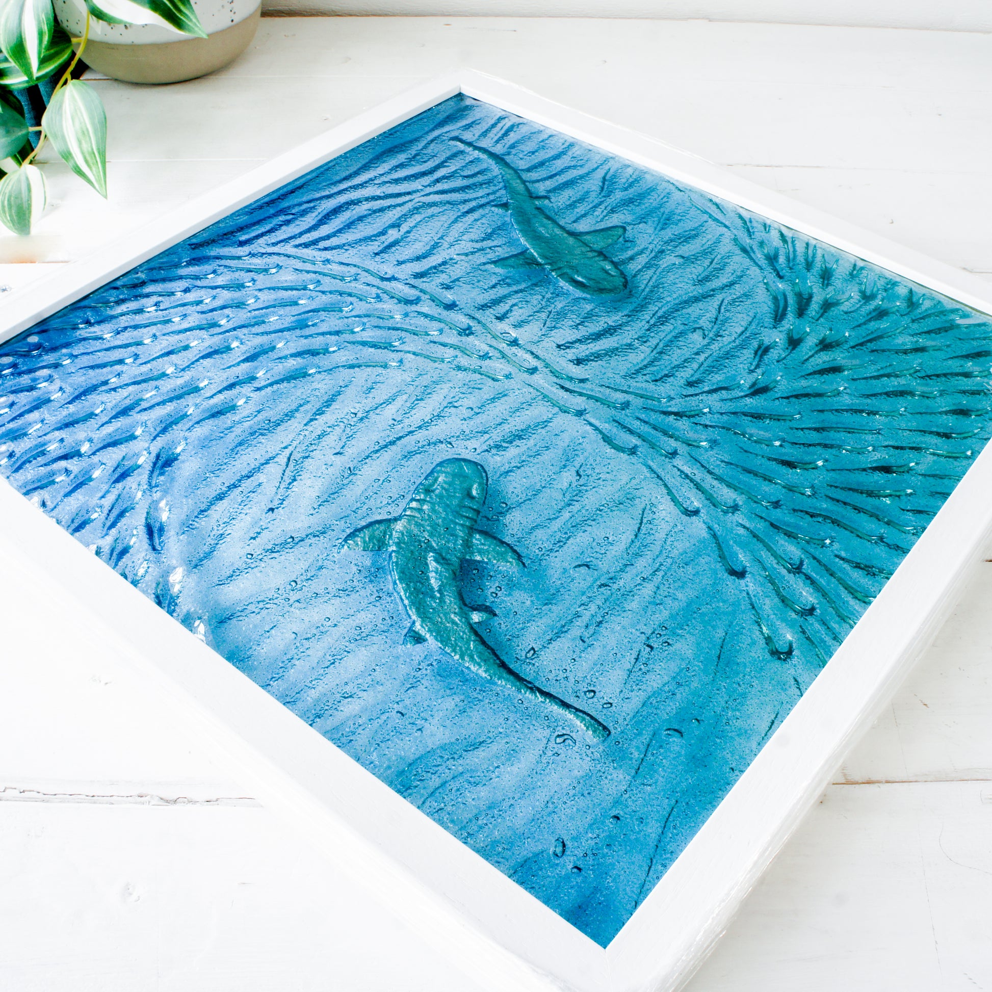 Artistic depiction of sharks swimming in a blue ocean with white waves on a white surface.