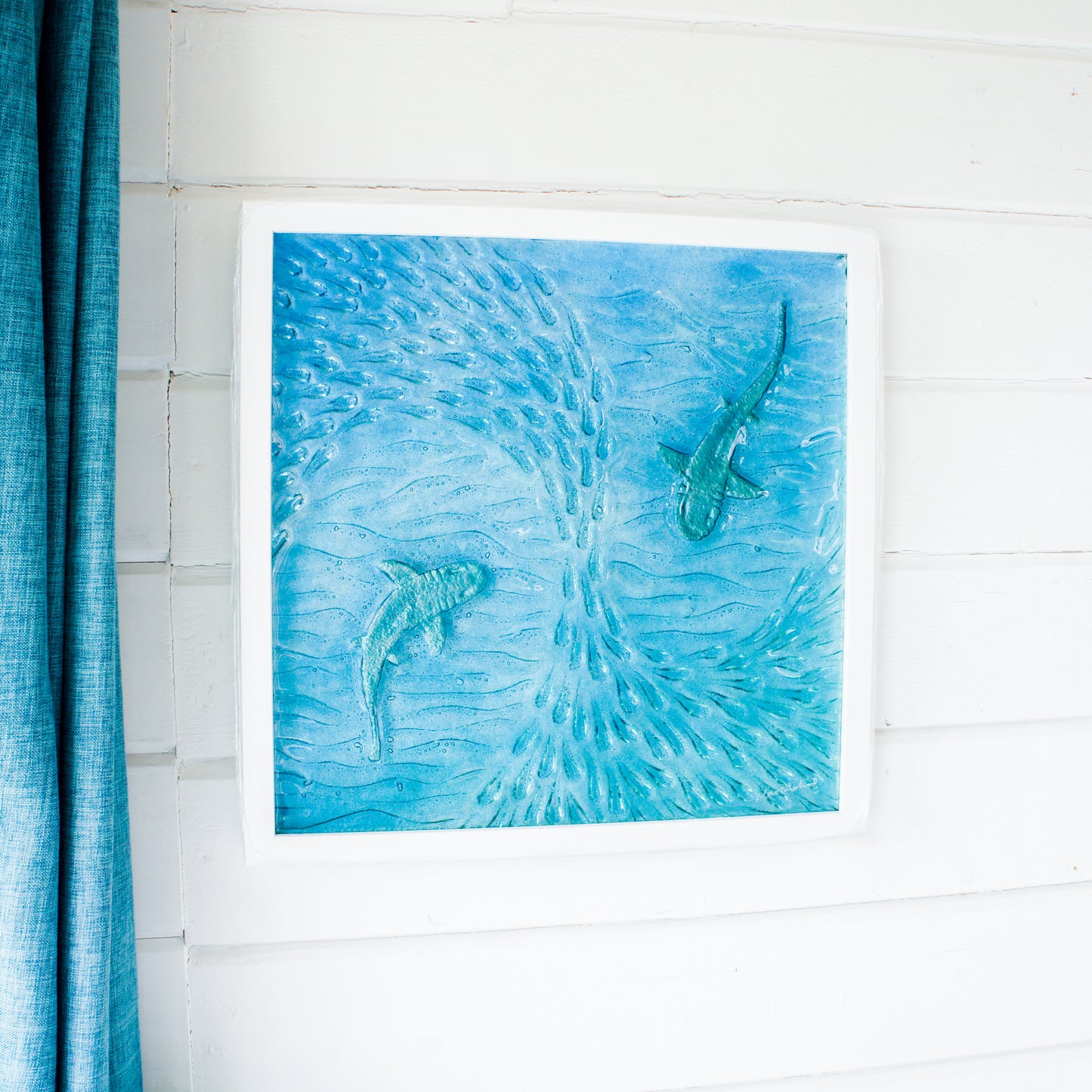 2 silver sharks swimming in blue teal turquoise sea with shoal of fish textured fused glass in square white wooden frame 45cm, ready to hang