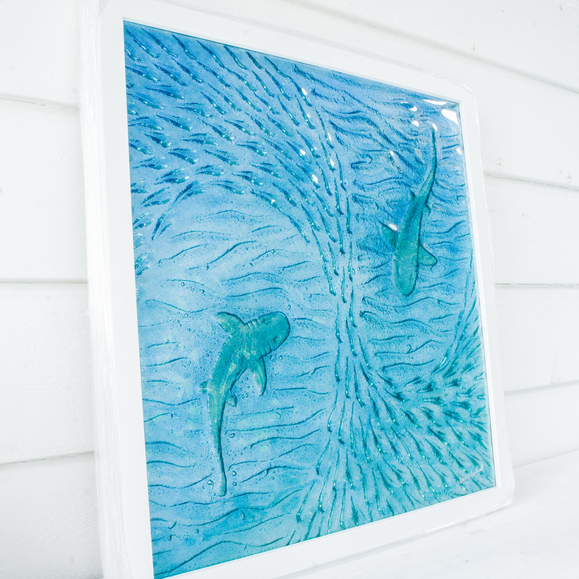 2 silver sharks swimming in blue teal turquoise sea with shoal of fish textured fused glass in square white wooden frame 45cm, ready to hang