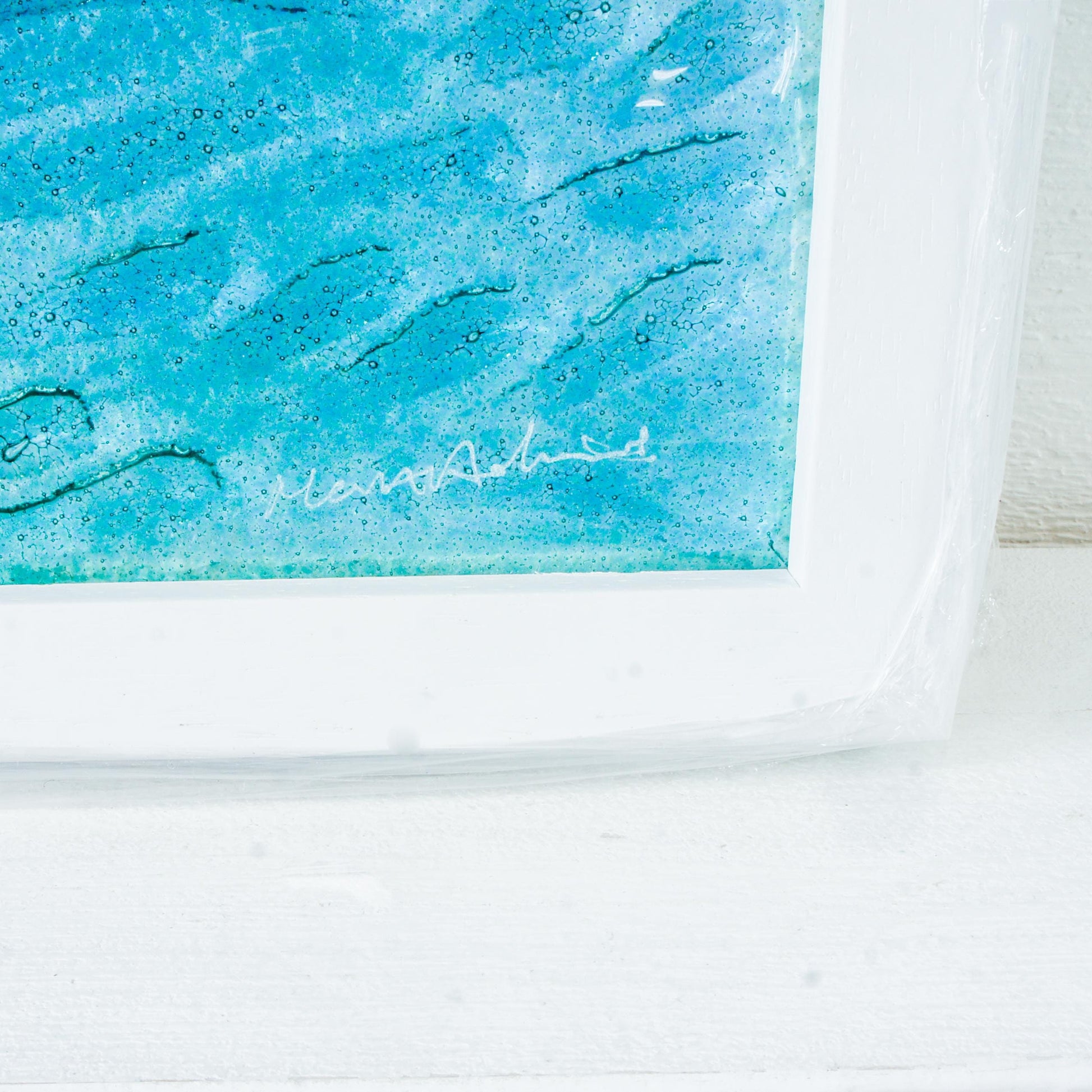 silver shimmering shark swimming in turquoise blue water with shoal of fish in textured fused glass in a white wooden frame 25x25cm (10")