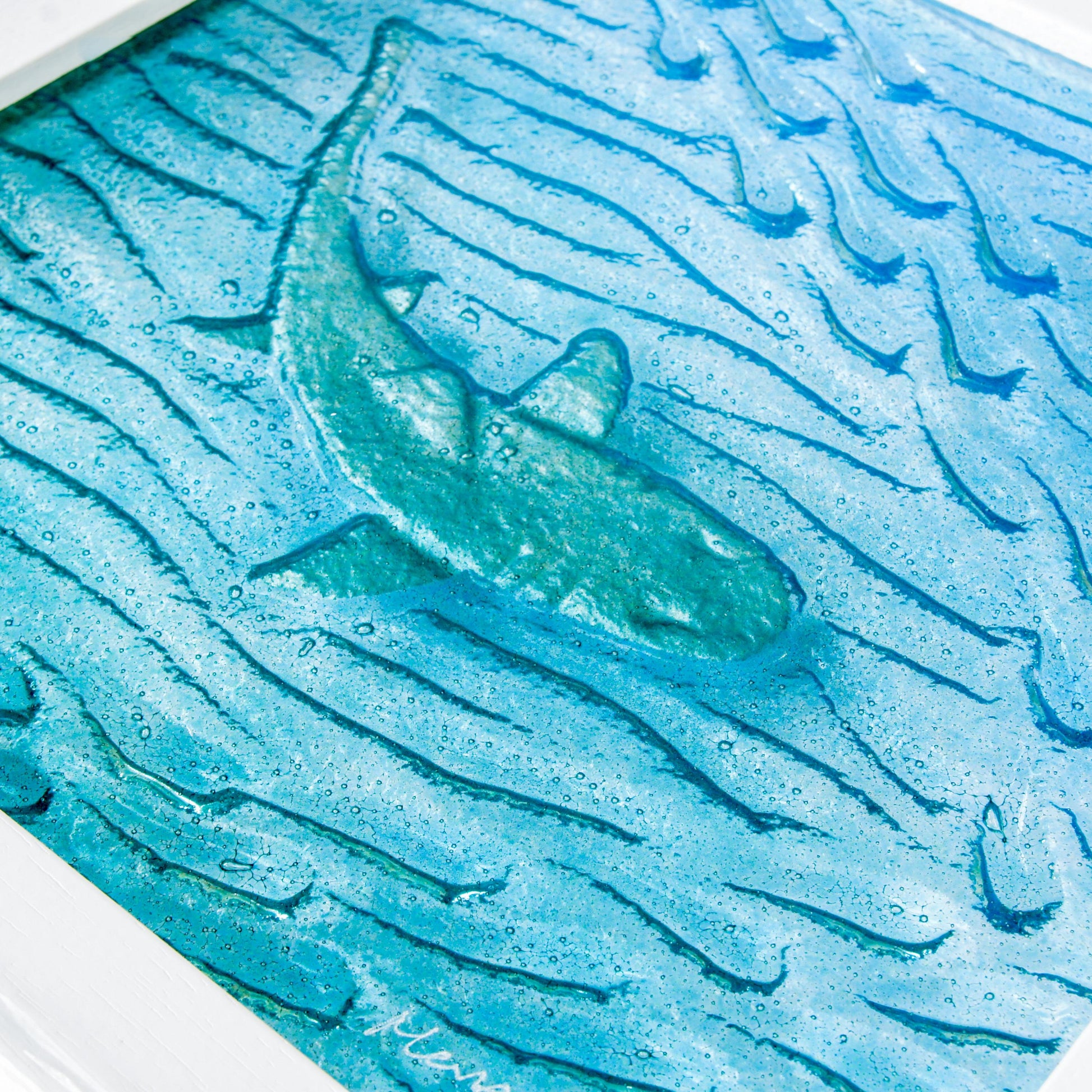 silver shimmering shark swimming in turquoise blue water with shoal of fish in textured fused glass in a white wooden frame 25x25cm (10")