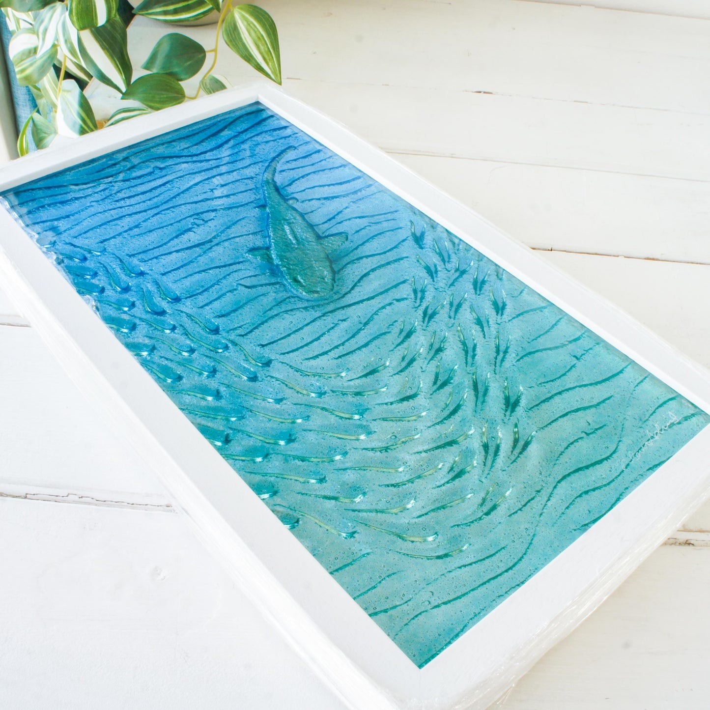 shark painted in silver swimming down with fish in blue sea fused glass wall art in a white wooden frame 25x45cm, view from bottom